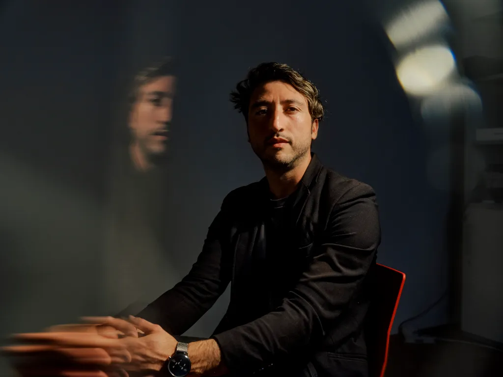 Marcello Ienca seated against a dark background with a blurred reflection.